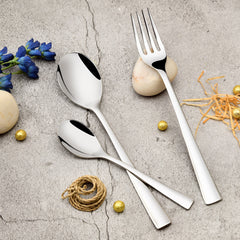 Elegant stainless steel fork and spoons on a textured stone surface with decorative elements around