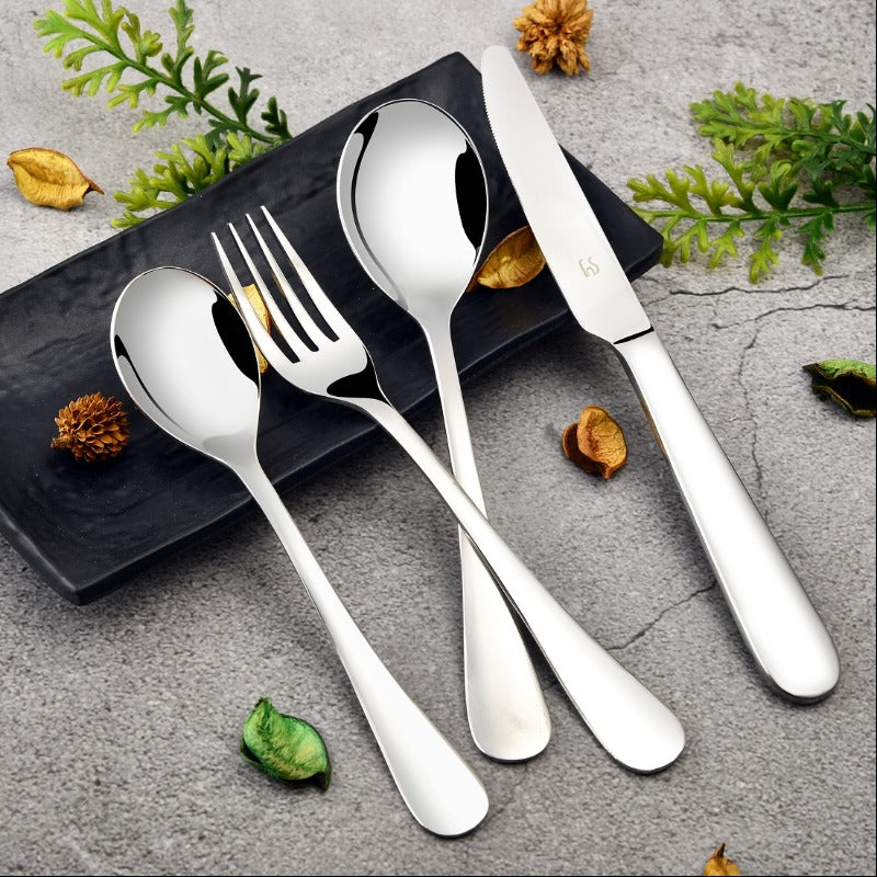 Elegant stainless steel cutlery set with knife, fork, and spoons on black plate and stone background.