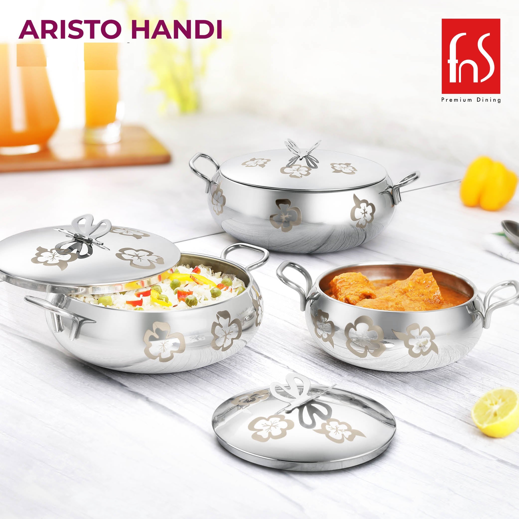 FNS Aristo Handi 3-piece stainless steel floral butterfly serving handi set with lids styled with rice, curry, and fresh vegetables on kitchen surface