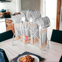 Stainless steel cutlery set with gold detailing displayed on dining table in a modern kitchen.