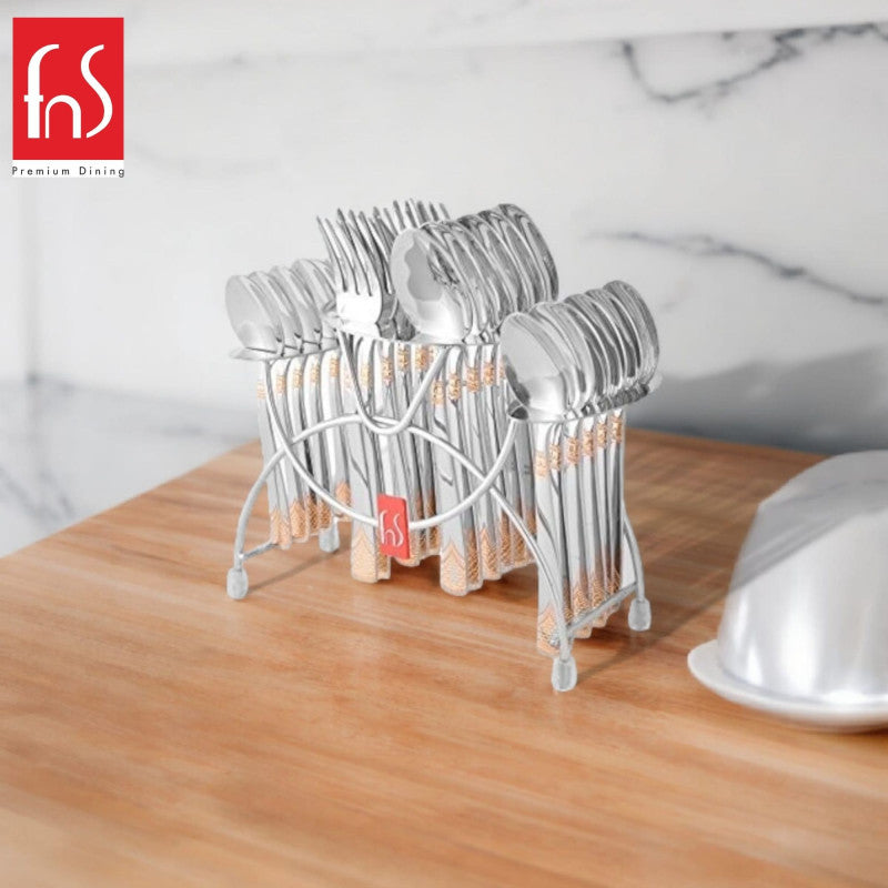 FnS stainless steel cutlery set with gold design placed on a wooden counter in modern kitchen.