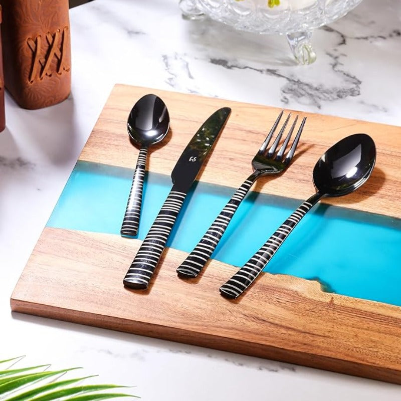 Black striped cutlery set displayed on wooden board with blue resin detail and marble background.