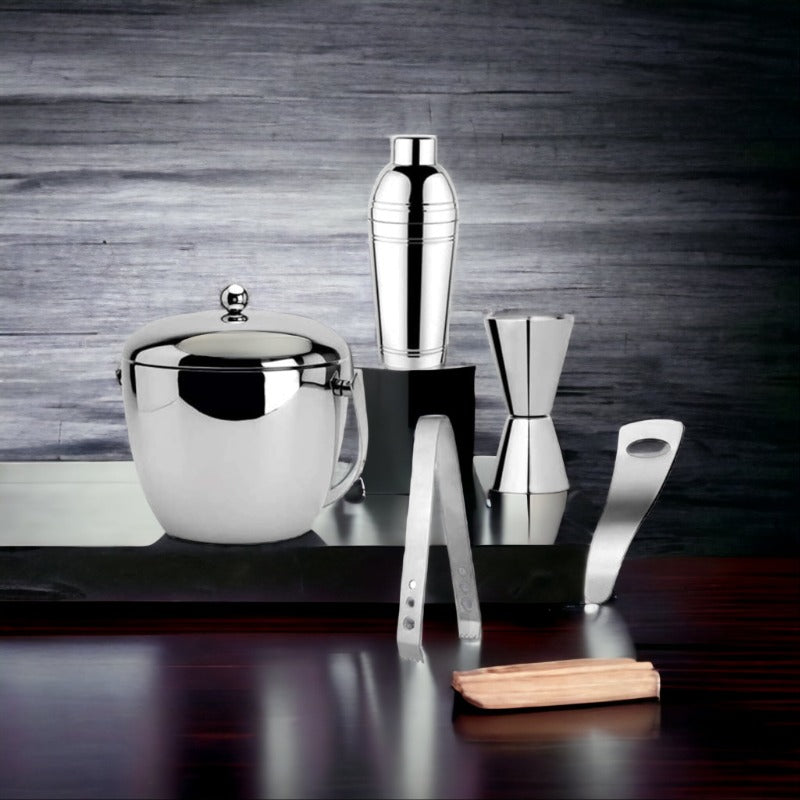 FNS bar tools arranged on rustic wooden board showing cocktail shaker, ice bucket, jigger, tongs, and opener in lifestyle setting