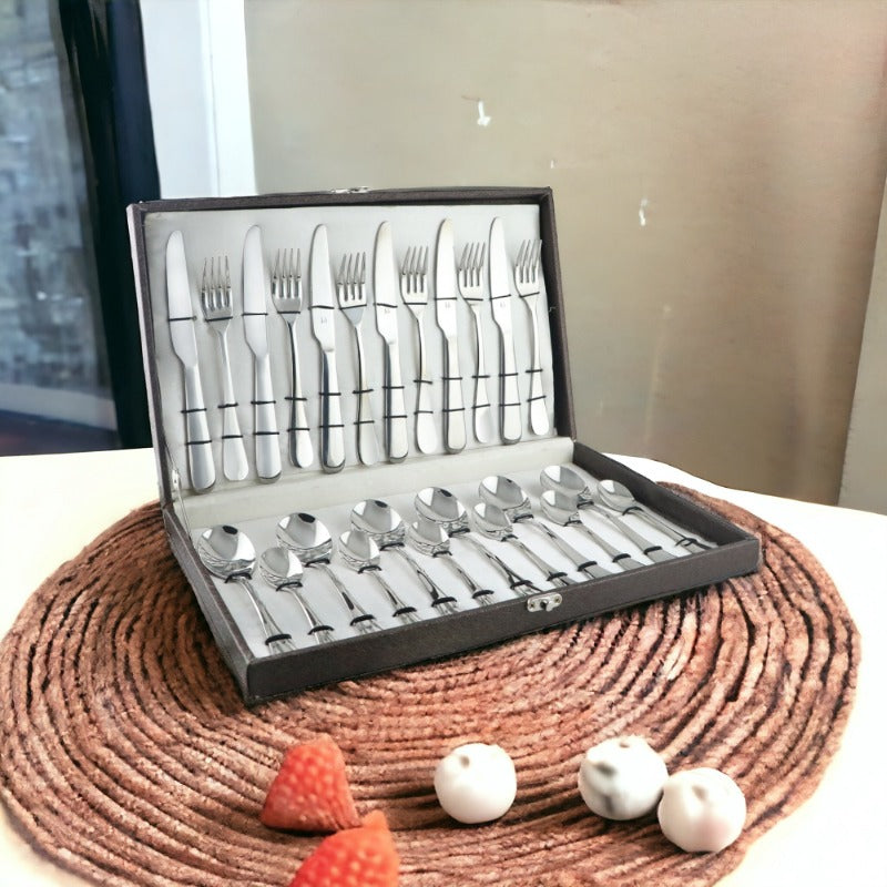 Elegant stainless steel cutlery set in a box, displayed on a woven mat with decorative fruit.