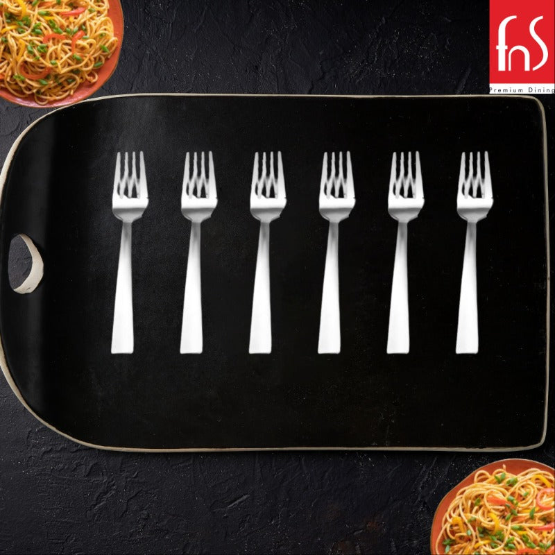 Six stainless steel dessert forks arranged on black serving tray with pasta dishes