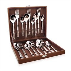 Three-piece patterned cutlery set placed on a dark ceramic plate with soft napkin and wooden table.