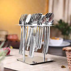 Shiny silver cutlery set with textured handles neatly arranged on vertical stand, placed on dining table.