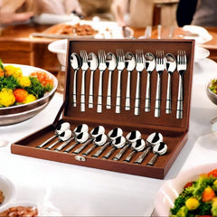 Elegant stainless steel cutlery set in brown case with patterned handles, displayed on festive dining table.