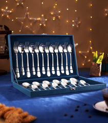 Premium silver cutlery set in a blue velvet box, placed on festive table with lights and stars.