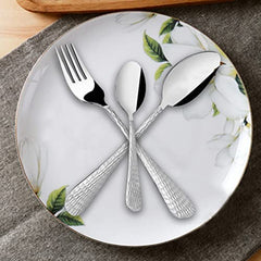 Three-piece cutlery set with textured handles arranged decoratively on a floral-patterned porcelain plate.