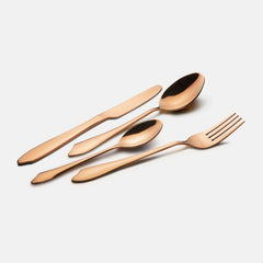 Elegant rose gold knife, fork, tablespoon, and teaspoon laid diagonally on plain white background.
