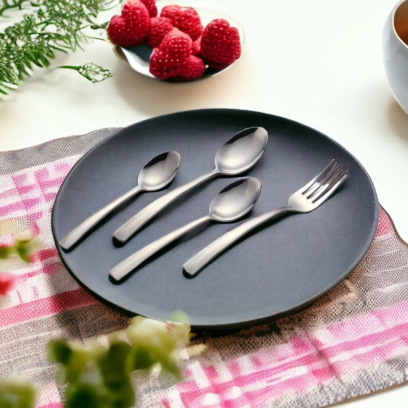 Elegant spoon and fork set arranged on matte black plate beside raspberries and checkered cloth.