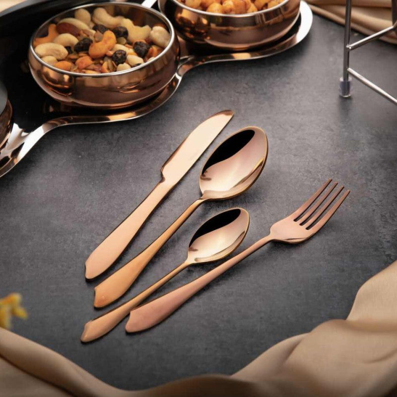Stylish rose gold utensils laid out beside glossy copper snack bowls on a dark textured surface.