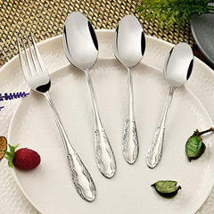Ornate stainless steel fork and spoons arranged on a ceramic plate with decorative elements and texture.
