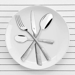 Knife, fork, and spoons with textured handles arranged in star shape on white dinner plate.