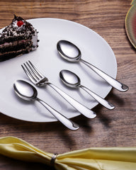 Montavo fork and spoons arranged on white plate beside cake slice and yellow napkin on table.