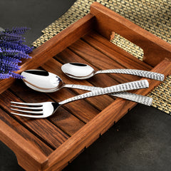Stylish hammered-handle fork and spoons displayed diagonally on a wooden tray with lavender decor.