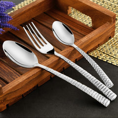 Fork and two spoons with hammered handles elegantly arranged on a wooden tray with decorative accents.
