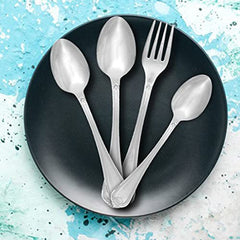 Stainless steel cutlery set with engraved handles displayed on black plate over aqua textured background.