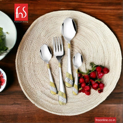 Premium silver and gold cutlery set placed on round jute mat beside fresh red berries.