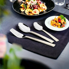 Three-piece cutlery set placed on black table with pasta dish and appetizer in stylish presentation.
