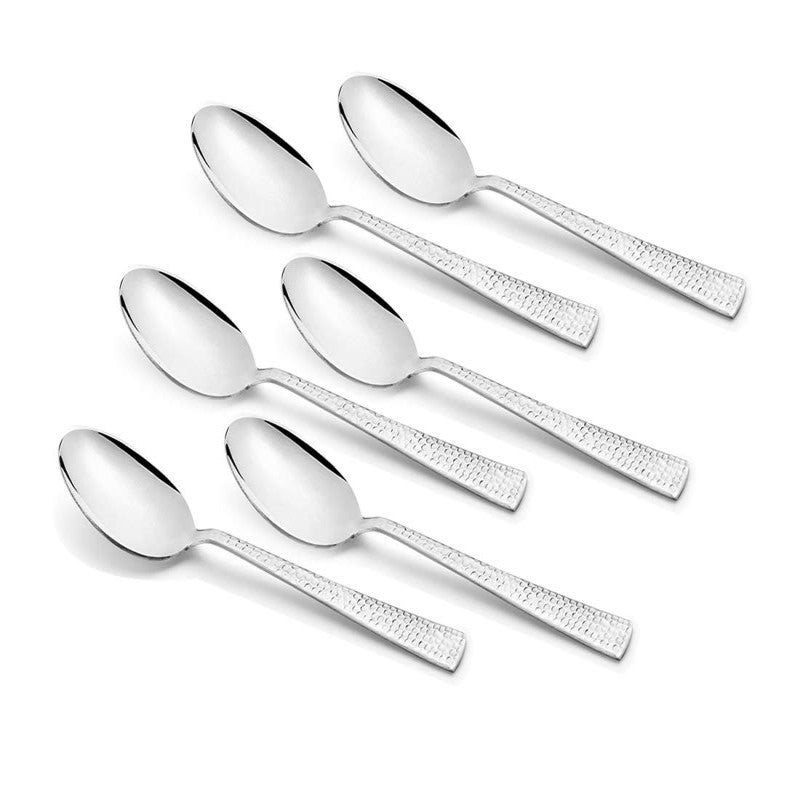 Set of six stainless steel spoons with textured handles, symmetrically arranged on white surface.