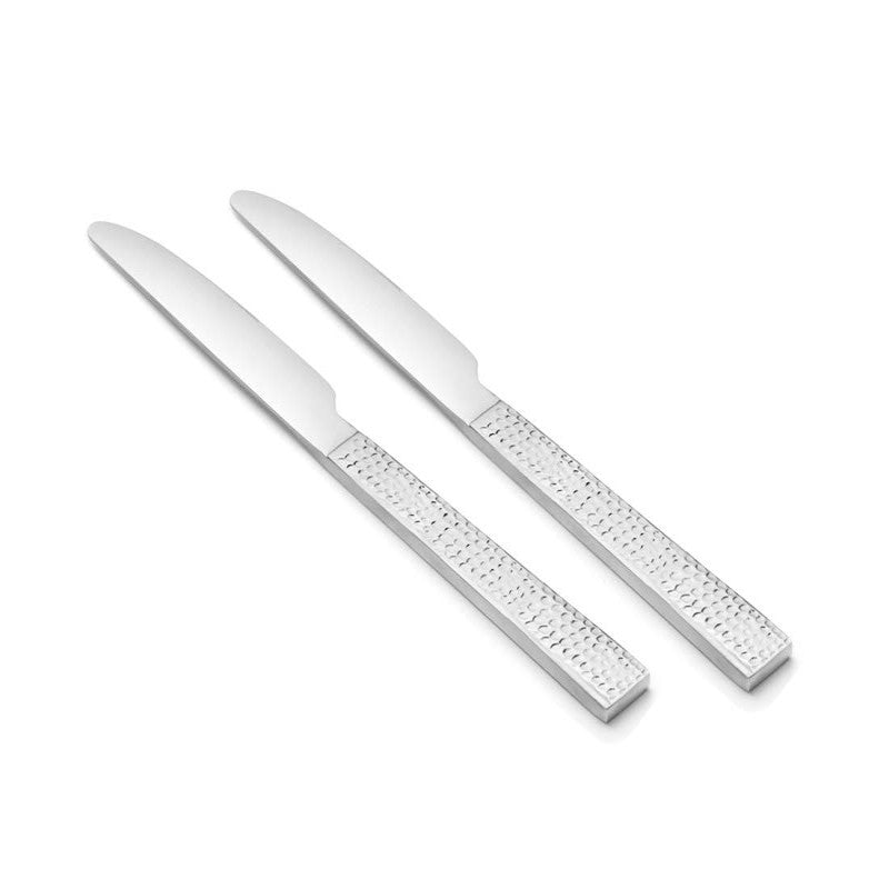 Pair of dinner knives with broad blades and textured stainless steel handles on plain white background.