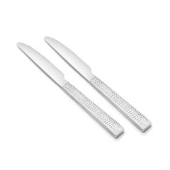 Pair of dinner knives with broad blades and textured stainless steel handles on plain white background.