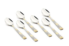 Six stainless steel teaspoons with decorative dual-tone gold and silver handles, arranged side-by-side.