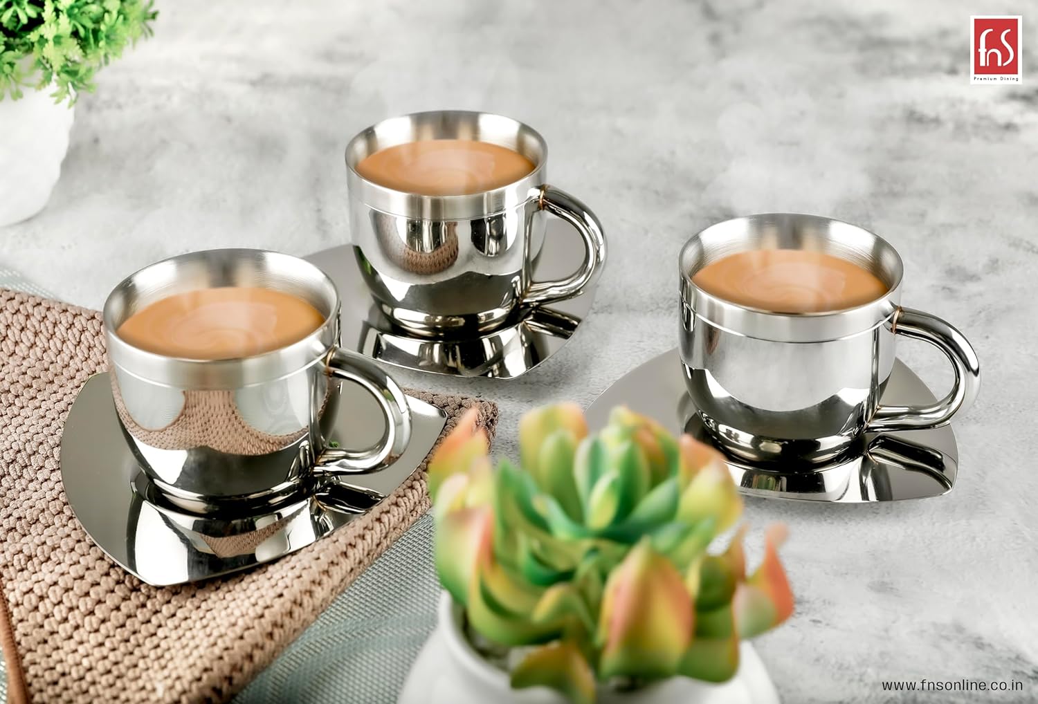 Three fns double wall stainless steel cups on triangular saucers filled with coffee, styled on grey marble surface with succulent plants and woven mat