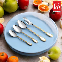 Elegant stainless cutlery with gold inlay arranged on blue plate, surrounded by colorful fresh fruits.