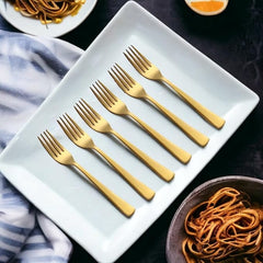 Six gold forks on white rectangular plate with pasta dishes nearby