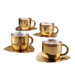 Set of 4 fns gold finish stainless steel tea cups with matching square saucers filled with steaming hot tea, styled on a grey surface with cookies and autumn foliage in the background