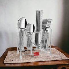 Complete stainless steel cutlery set in stand, placed on wooden table with woven beige mat.