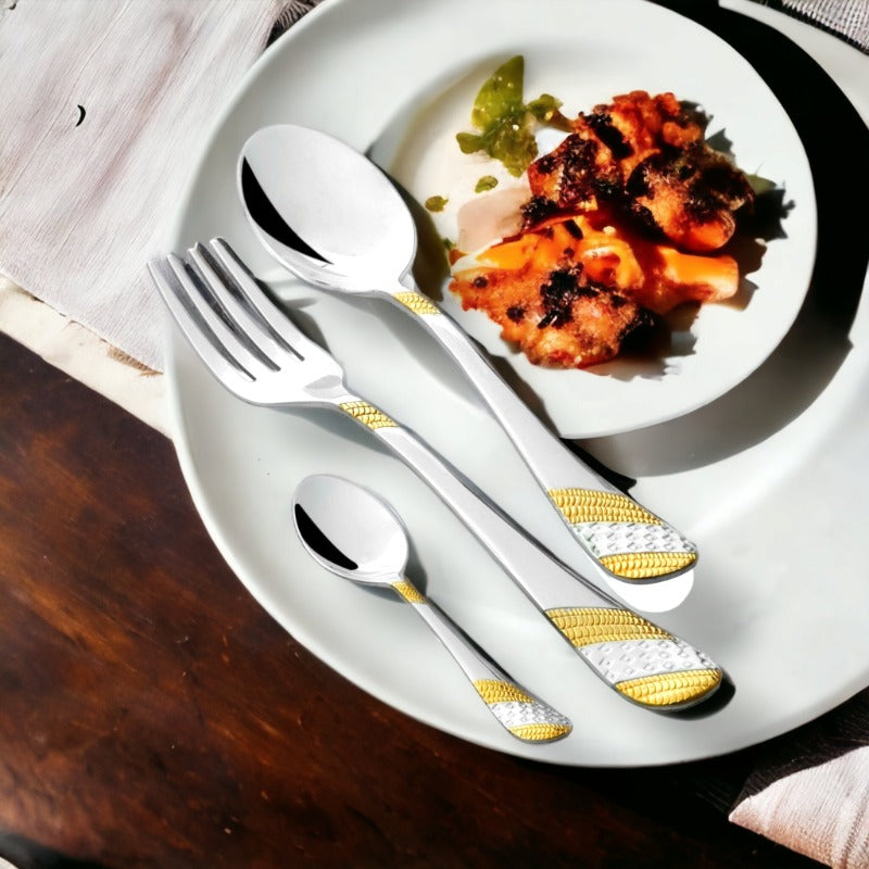 Gold-accented cutlery set placed on a white plate with a side dish of grilled food.