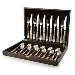 Luxury cutlery set with gold-accented handles arranged in open presentation case with dark velvet lining.