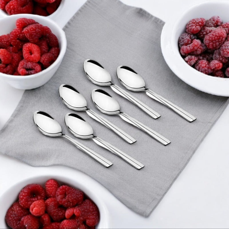 FNS Nile 6-piece stainless steel coffee spoons with sleek handles and mirror-polished bowls displayed on gray linen napkin with white bowls of fresh red and frozen raspberries
