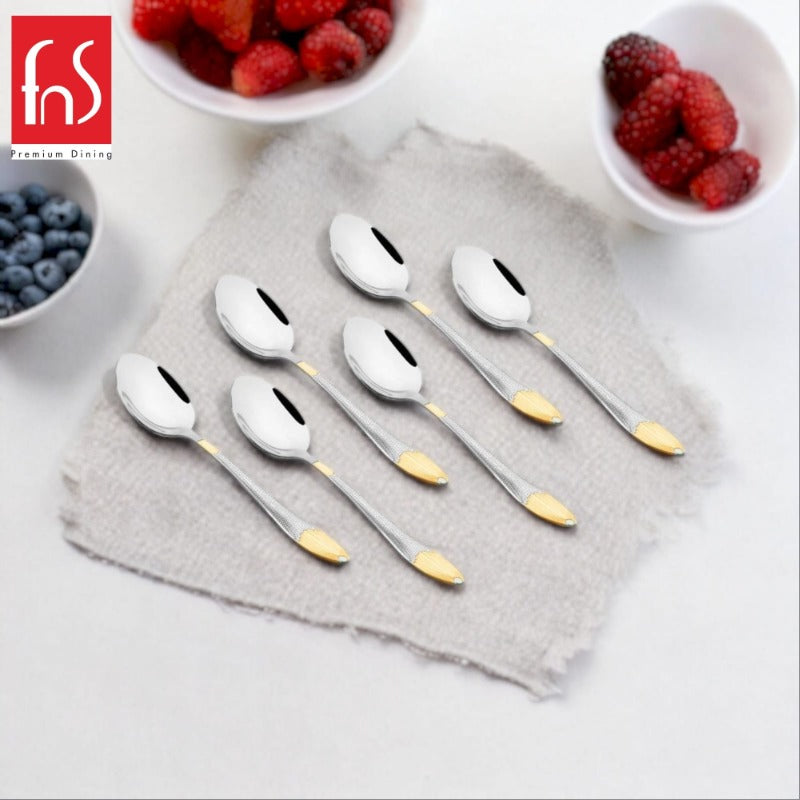 FNS Premium Dining Passion 6-piece baby spoons with gold accent details and textured silver handles displayed on gray linen napkin with fresh blueberries and raspberries in white bowls