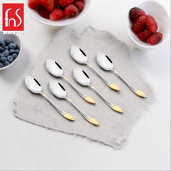 FNS Premium Dining Passion 6-piece baby spoons with gold accent details and textured silver handles displayed on gray linen napkin with fresh blueberries and raspberries in white bowls