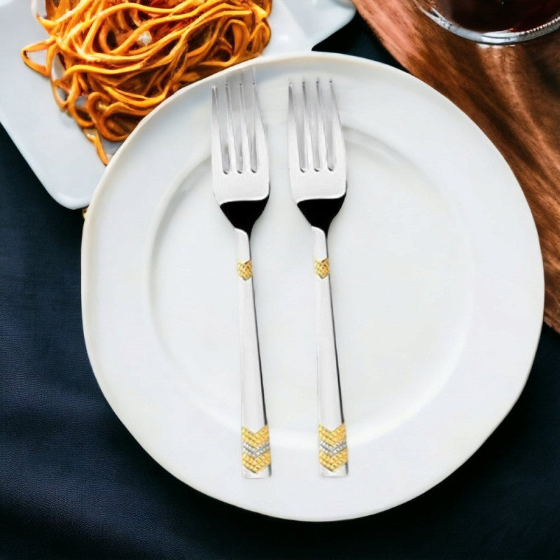 Two silver forks with gold accents on white plate beside pasta bowlRetry