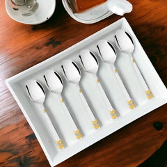 FNS Raga 6 piece dinner spoon set with 24 karat gold plated chevron pattern handles displayed on white rectangular tray beside tea service