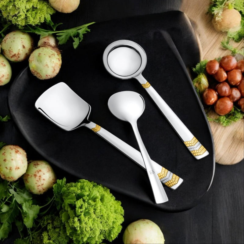 FNS Raga 3-piece serving set with 24-karat gold plated chevron accents on black plate with fresh vegetables and greens lifestyle setting