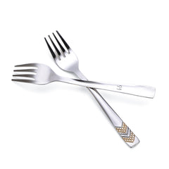 Two crossed stainless steel fruit forks with geometric gold chevron handles, showing premium construction and elegant design