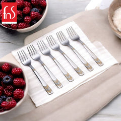 Six fruit forks arranged in white box with mixed berries, showcasing elegant geometric gold-accented handles for dining