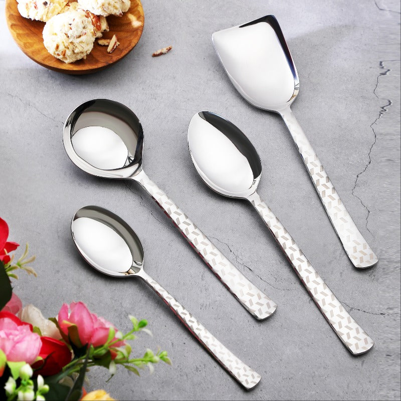 FNS Rhombo 4-piece stainless steel serving spoon set with geometric laser design handles on gray surface with flowers and ice cream