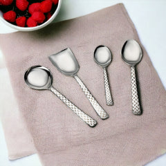 FNS Rhombo stainless steel 4-piece serving set arranged on pink linen placemat with bowl of fresh strawberries for elegant table setting