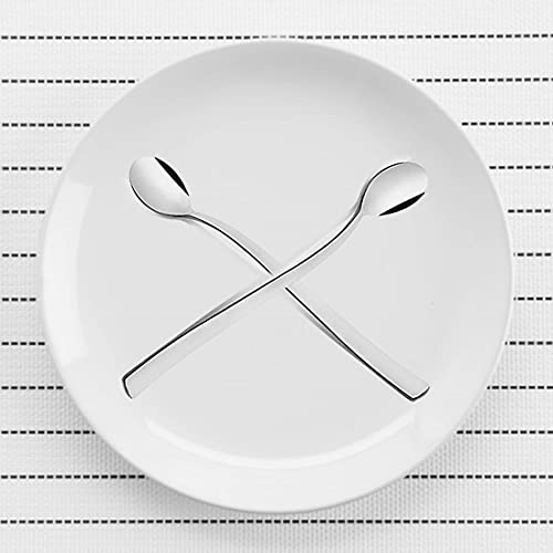 Two FNS Slim Line long drink spoons crossed on white plate displaying elegant curved design and mirror finish, modern minimalist beverage cutlery collection.
