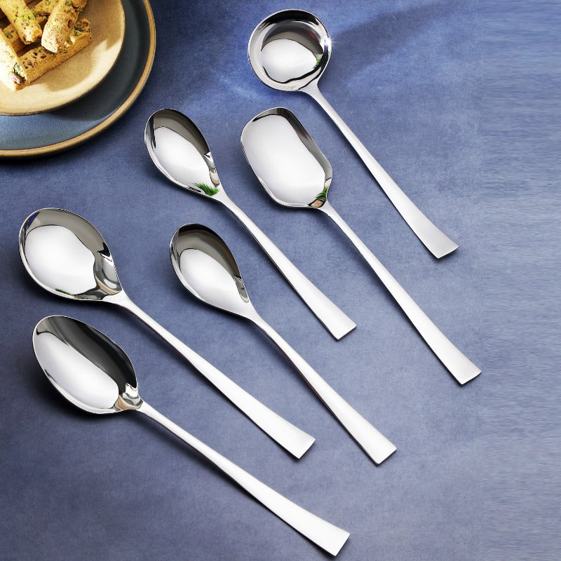 FNS Slim Line 6-piece premium stainless steel serving spoon set displayed on blue tablecloth with appetizer plate, showcasing sleek modern slim handle design.