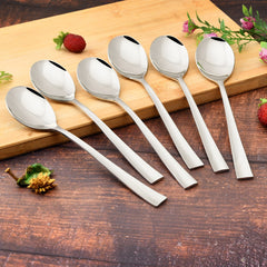 FNS Slimline 6-piece baby dessert spoon set with sleek flat handles displayed on wooden cutting board with fresh strawberries and pink flowers decoration.