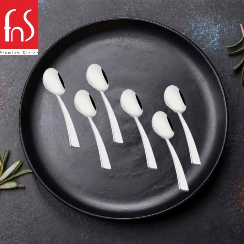 FNS Solo 6-piece stainless steel dinner spoon set with flat handles displayed on black matte plate with olive leaves decoration, modern minimalist cutlery.